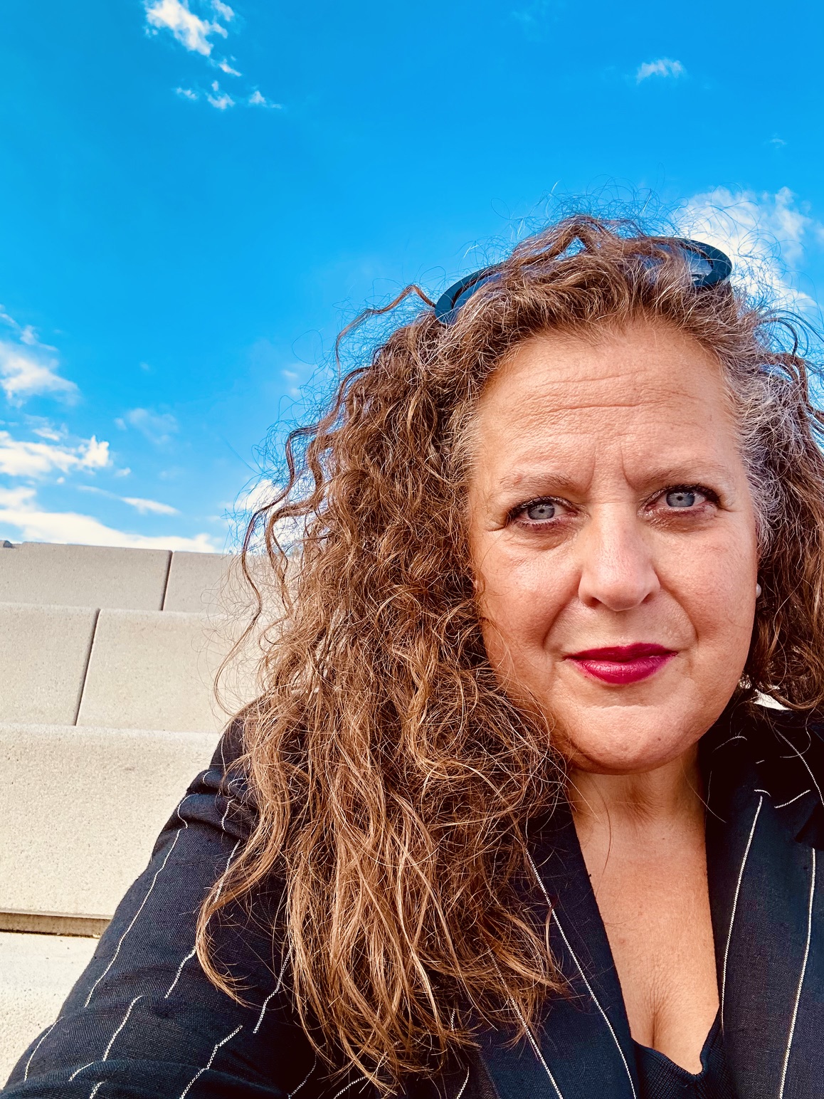 Sabine Gillessen auf dem Foto, sitzend vor blauem Himmel