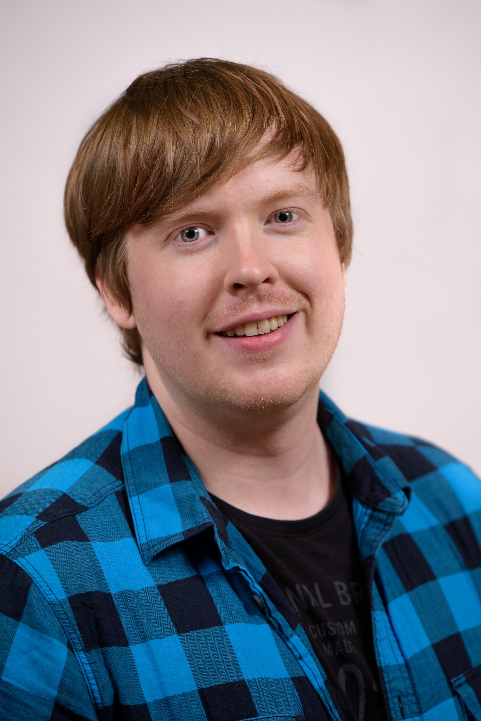 Man with pale, white skin, redish hair and blue and black checkered shirt